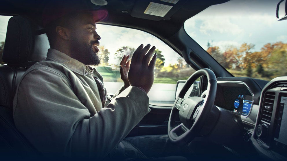 Man removing hands from the steering wheel while using BlueCruise on a sunny day